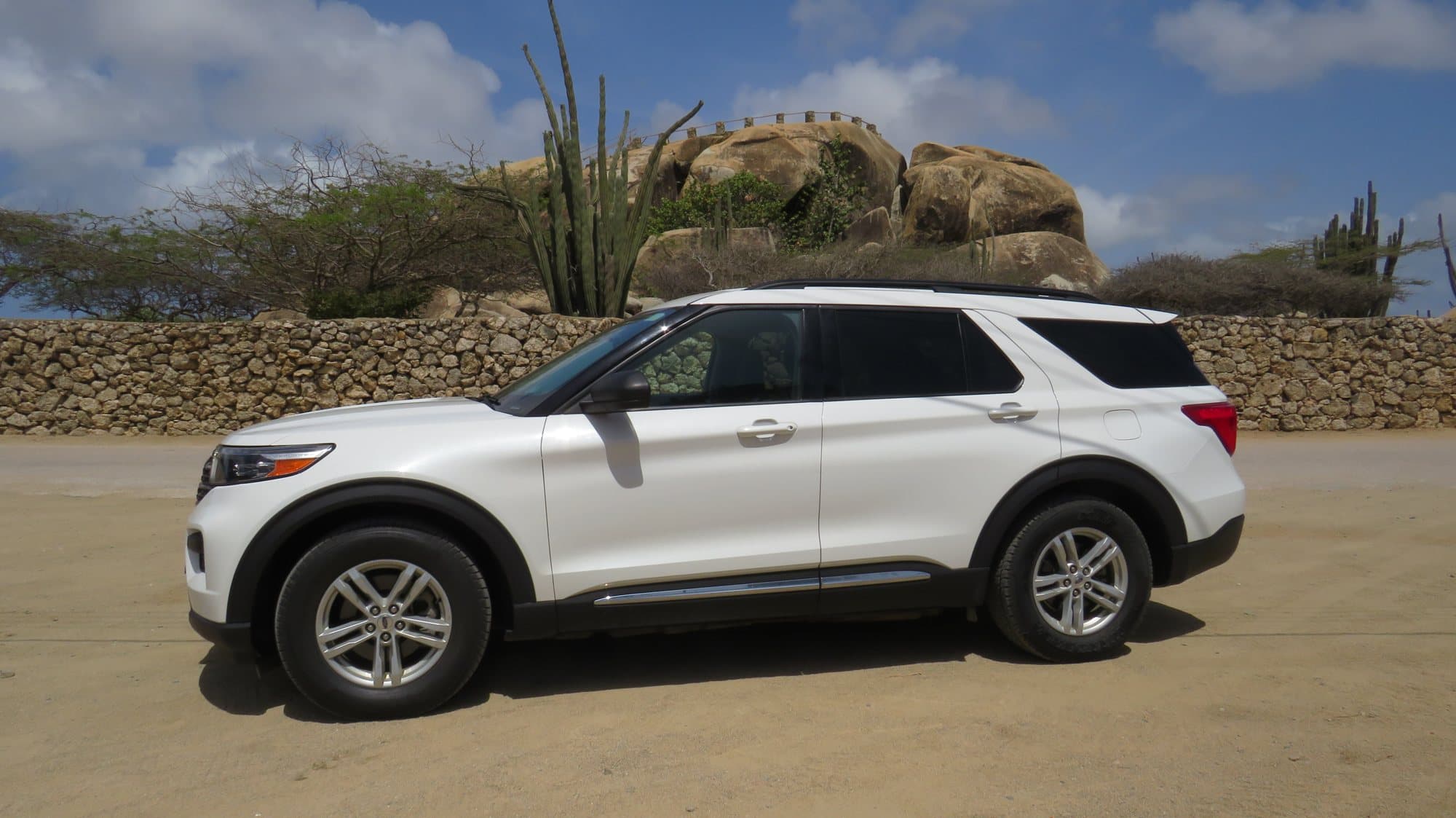A white Ford Explorer parked beside the Ayo rock formations in Aruba