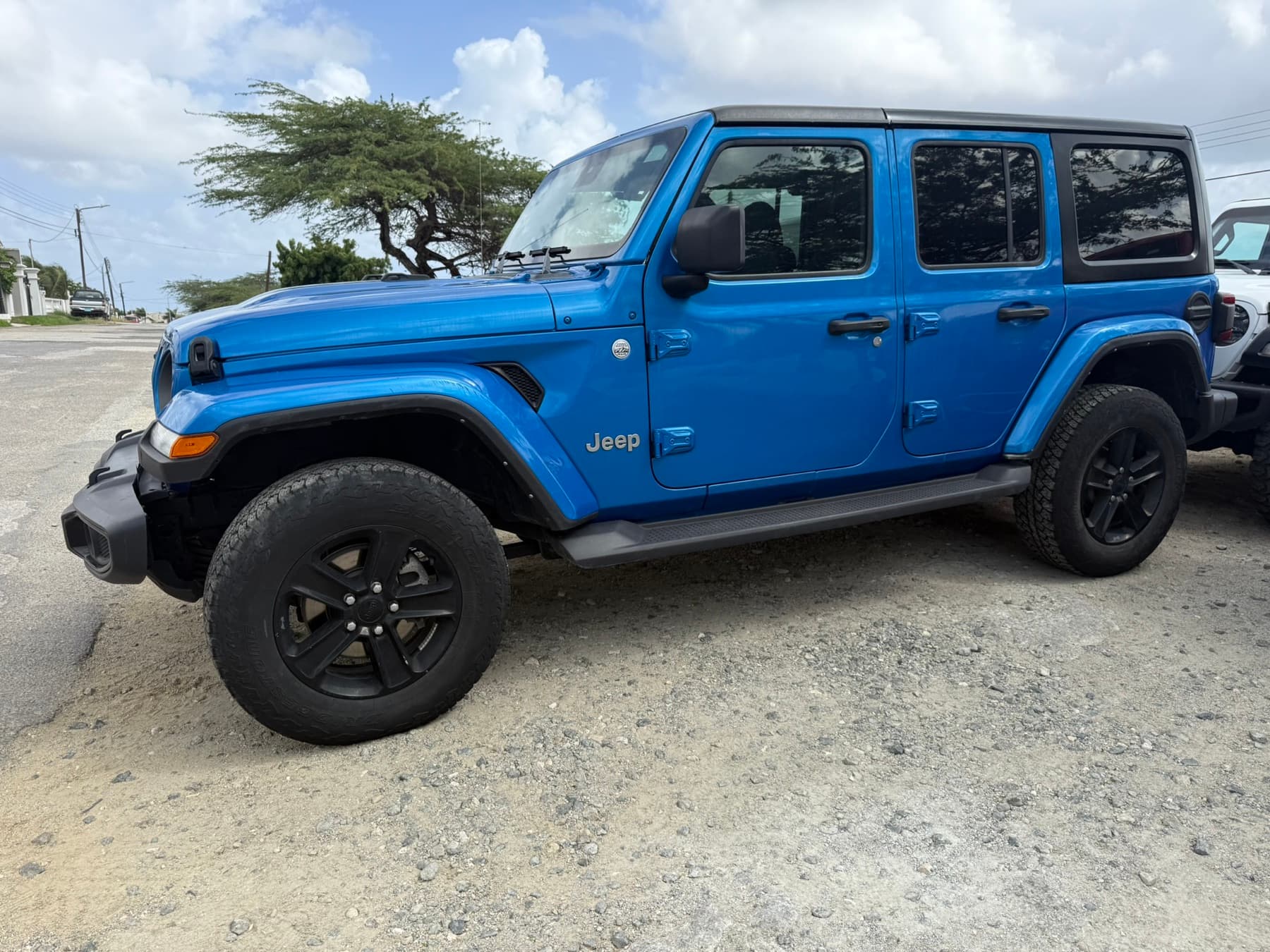 A blue Jeep Wrangler parked on a paved lot