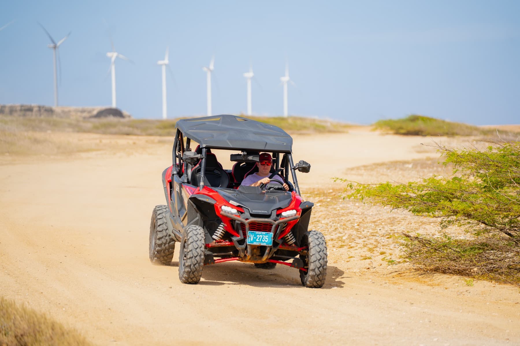 Red UTV climbing a dune on Aruba's north coast