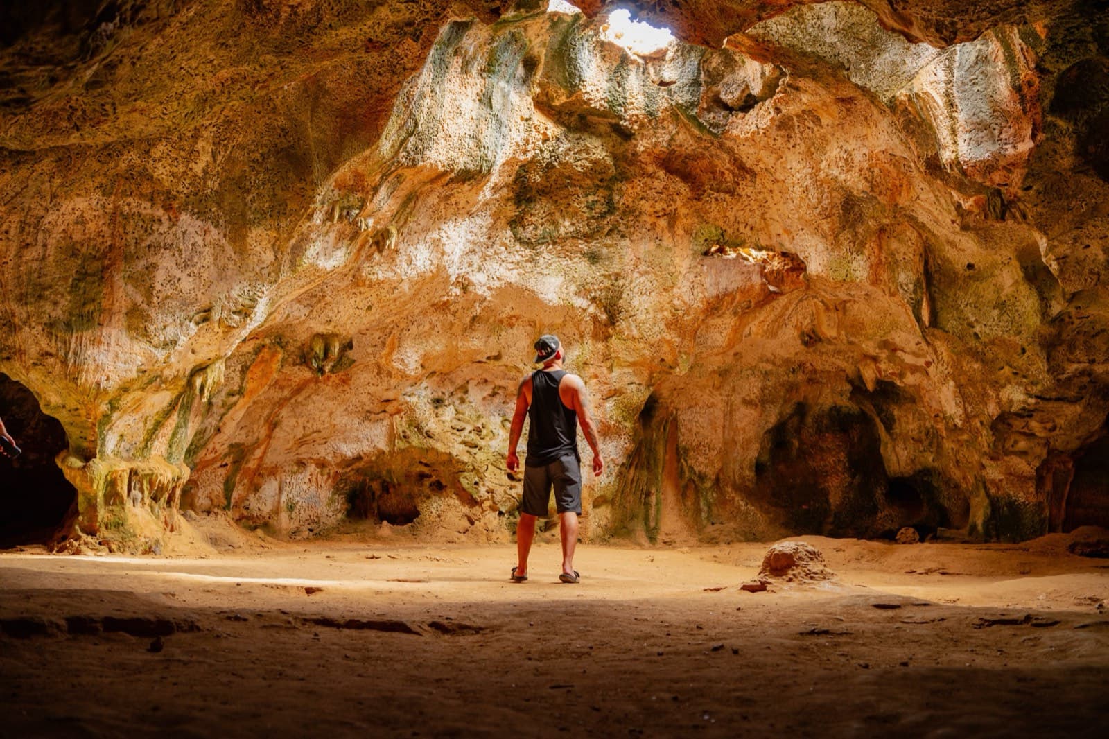 A visitor standing inside a sunlit cave
