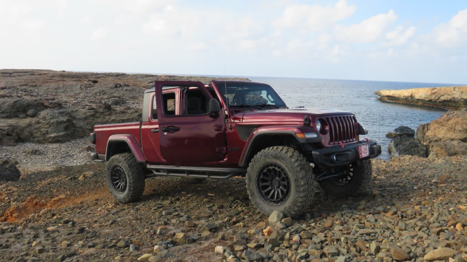 Maroon Jeep Gladiator on the rocky coast