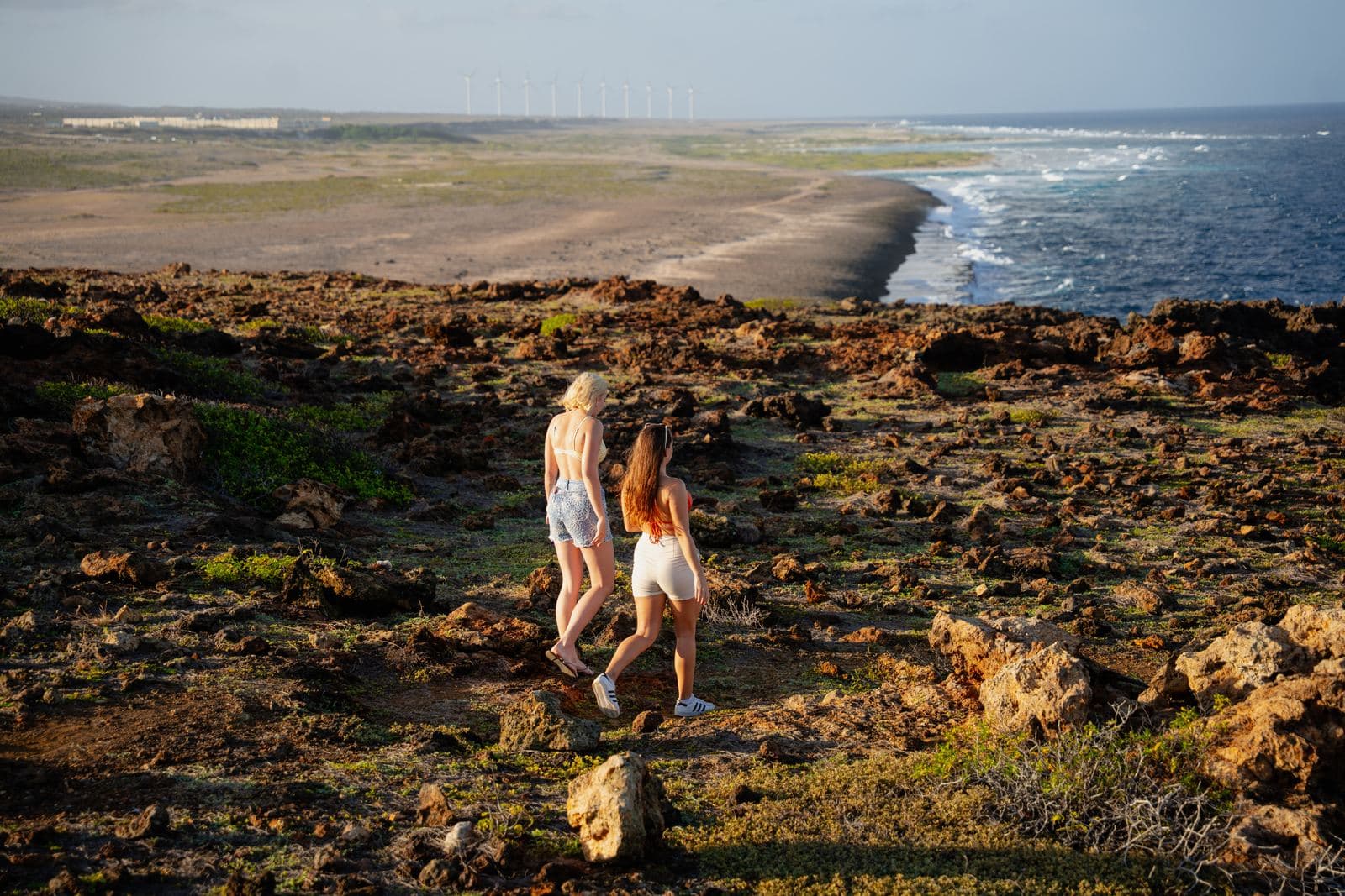 Two visitors walking along a rocky stretch of Aruba's coast